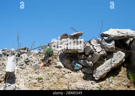 A pile of gray concrete debris against a blue textured sky with feathery white clouds. Background. Stock Photo