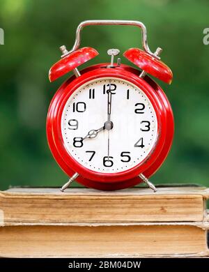 Retro red alarm clock standing on old books Stock Photo