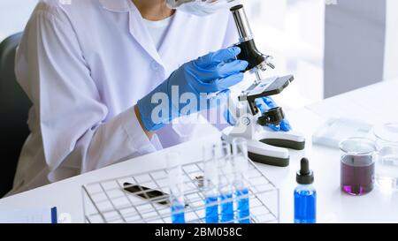 Young Asian scientist Working looking through a  microscope doing research for analyzing a Experiments sample in a forensic laboratory Stock Photo