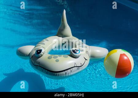 Inflatable shark rubber ring and inflatable beach ball floating in a villa swimming pool in Paphos on the island of Cyprus Stock Photo