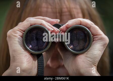 Woman with binoculars to her eyes. Stock Photo