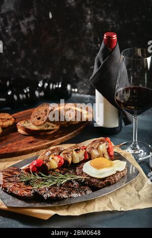 Assorted grilled meat with wine table setting, food photo concept. Beef, mornings, pork and lamb are beautifully laid out on a plate. Stock Photo