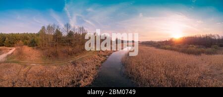 Spring rural landscape in the evening. Aerial view. Panoramic view of the narrow river during sunset. Panorama 180 from 21 images