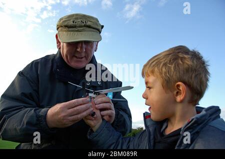 Grandfather and adopted grandson playing with balsa plane UK Stock Photo