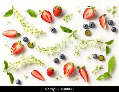 flat lay composition of blooming bird cherry and fresh berries on white background, top view Stock Photo
