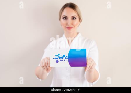 Portrait of attractive beautician standing against wall and showing new beauty product at camera while recommending it Stock Photo