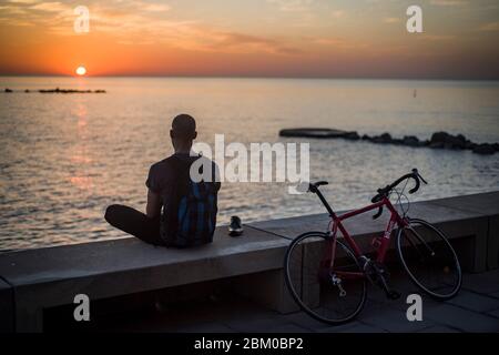 Barcelona, Spain. 06th May, 2020. May 6, 2020, Barcelona, Catalonia, Spain - A man watches the sun rise over the Mediterranean Sea in Barcelona. De-escalation measures on the coronavirus confinement allow the Spaniards to go out for a walk or do sports a few hours a day following certain schedules, today Spanish Congress votes on new extension to state of alarm. Jordi Boixareu/Alamy Live News Credit: Jordi Boixareu/Alamy Live News Stock Photo