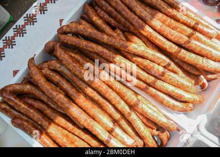 Sausages hanging outside during outdoor street food festival. Sausage production line. Sausage on the counter for the smokehouse. Industrial manufactu Stock Photo