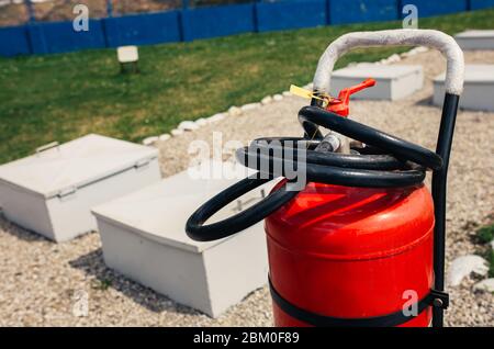 Fire close-up extinguishers available in fire emergencies at a petrol station background. Stock Photo