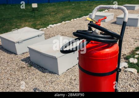 Fire close-up extinguishers available in fire emergencies at a petrol station background. Stock Photo