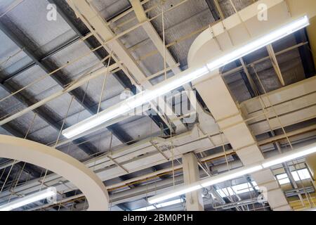 Ceiling mounted Lamp pipes and air ducts and communication system in the hall Stock Photo