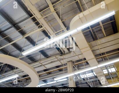 Ceiling mounted Lamp pipes and air ducts and communication system in the hall Stock Photo