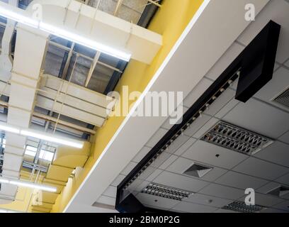 Ceiling mounted Lamp pipes and air ducts and communication system in the hall Stock Photo