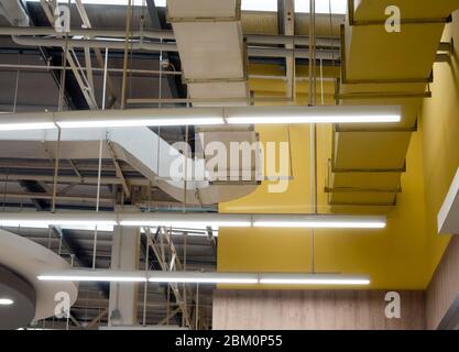 Ceiling mounted Lamp pipes and air ducts and communication system in the hall Stock Photo