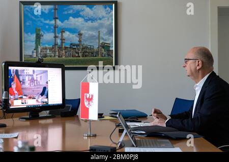 Potsdam, Germany. 06th May, 2020. Dietmar Woidke (SPD), Prime Minister of Brandenburg, is listening to the speech of Chancellor Angela Merkel (CDU) on the computer monitor in the State Chancellery during the Federal-Länder Conference. Credit: Soeren Stache/dpa/Alamy Live News Stock Photo