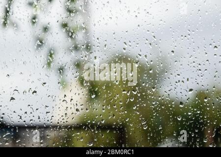 Raindrops on the window pane. Blurred background outside the window in the rain. Stock Photo