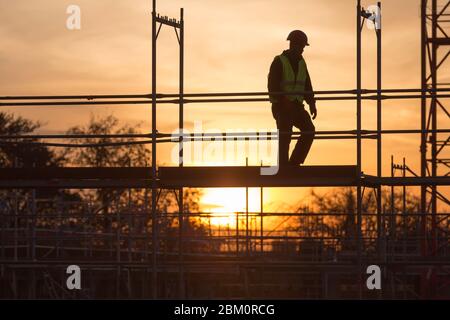 worker on scaffolding at sunset Stock Photo