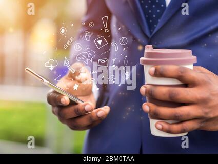 African businessman holding coffee and using brand new mobile phone Stock Photo