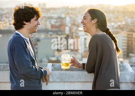 Young couple chatting and having a beer on the terrace Stock Photo