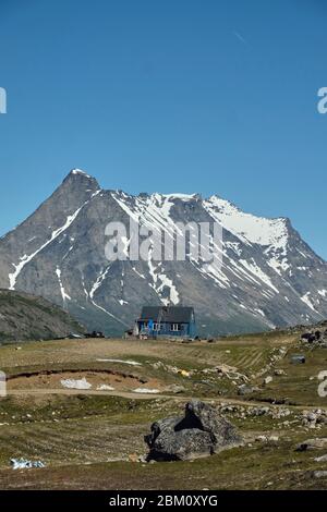 Lonely house near the greenlandic village of Tasiusaq with epic mountain ranges in the background Stock Photo