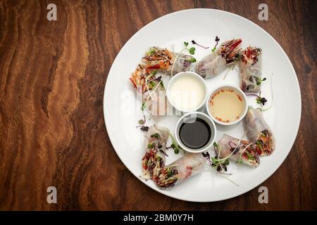 asian fresh vegetable vegan spring rolls with sauces on wood restaurant table in hanoi vietnam Stock Photo