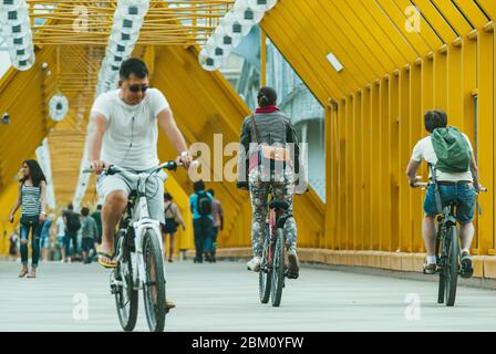 Moscow, Russia - JUNE 1, 2014: Young couple and man on bicycles cross the Bogdan Khmelnitsky pedestrian bridge Stock Photo