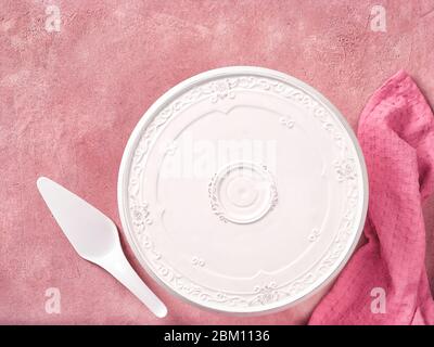 Empty cake plate and spatula on pink concrete background, top view Stock Photo