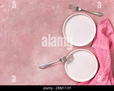 Two empty dessert plates, forks and napkin on pink concrete background. Top view, space for text Stock Photo
