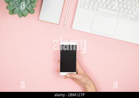 Womens home workspace. Girl Blogger works with phone and laptop. Freelance concept. Teleworker texting using laptop and internet, working online. Stock Photo