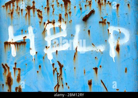 Blue metal surface with brown rusted spots and text help in white. Urban graffiti background. Stock Photo