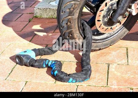 Lockable chain on wheel of a scooter for protection against theft. Stock Photo