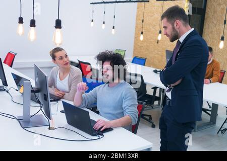 Working group discussing ideas for project sharing opinions while checking business plan on laptop, female web designer presenting to boss her job usi Stock Photo