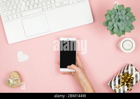Womens home workspace. Girl Blogger works with phone and laptop. Freelance concept. Teleworker texting using laptop and internet, working online. Stock Photo
