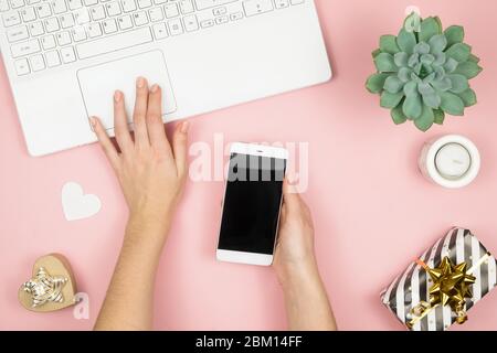 Womens home workspace. Girl Blogger works with phone and laptop. Freelance concept. Teleworker texting using laptop and internet, working online. Stock Photo