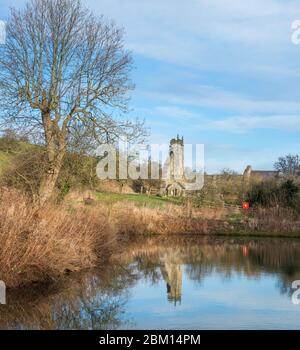 The ruined church in Wharram Percy deserted medieval village reflected in the fish pond Stock Photo