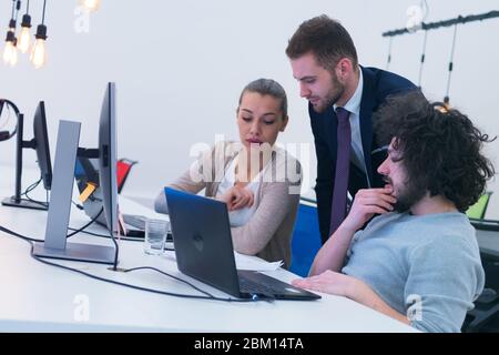 Working group discussing ideas for project sharing opinions while checking business plan on laptop, female web designer presenting to boss her job usi Stock Photo
