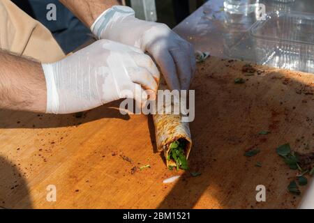 Traditional Turkish pizza, called Lahmacun, being prepared with meat, onion and parsley, displayed on a wooden table at a a street food market