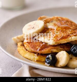 Stack of buttermilk pancakes topped with bananas, syrup and blueberries. Stock Photo