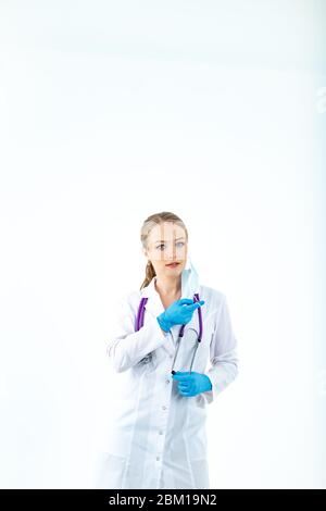 doctor nurse puts on a protective mask. A nurse in a respiratory mask. Put on masks. Wear gloves. beautiful blonde doctor shows how to put on a protec Stock Photo