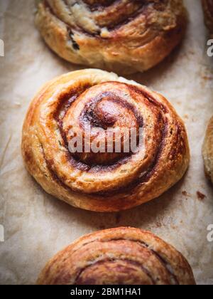 Close up of a cinnamon bun on a baking paper shot from above Stock Photo