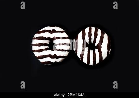 Glazed striped donuts on dark background. Party food concept with copy space. Top view. Stock Photo