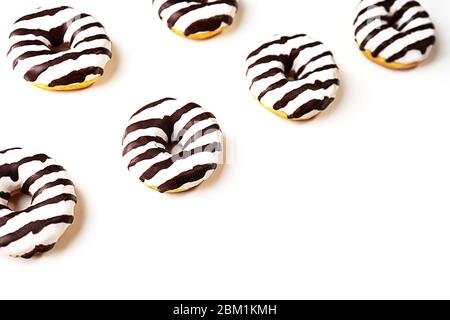 Glazed striped donuts on white background. Party food concept with copy space. Top view. Stock Photo