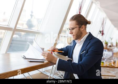 Image of concentrated handsome young businessman indoors in office work with paper documents. Stock Photo