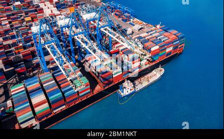 Concept of logistics and transportation containers cargo ship in port. Crane loads ship. Aerial top view. Stock Photo