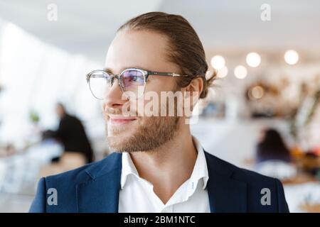 Image of handsome concentrated young businessman indoors in office looking aside. Stock Photo