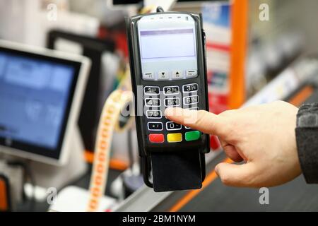 Male hand typing pin code card while paying with it at cash desk of supermarket Stock Photo