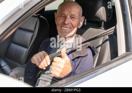 Emotional portrait of a positive and happy mature Hispanic old man wearing casual clothes and wireless headphone, with a smile on his face staring Stock Photo