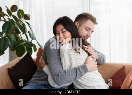 Multicultural Couple Hugging Reconciling After Quarrel At Home Stock Photo