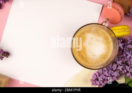 Blank note sheet surrounded by lilac colors and colorful macaroons. Stylish minimalistic workplace concept. Top view with copy space Stock Photo