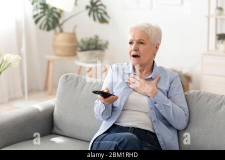 Coronavirus News. Shocked Senior Woman Watching Tv At Home Stock Photo